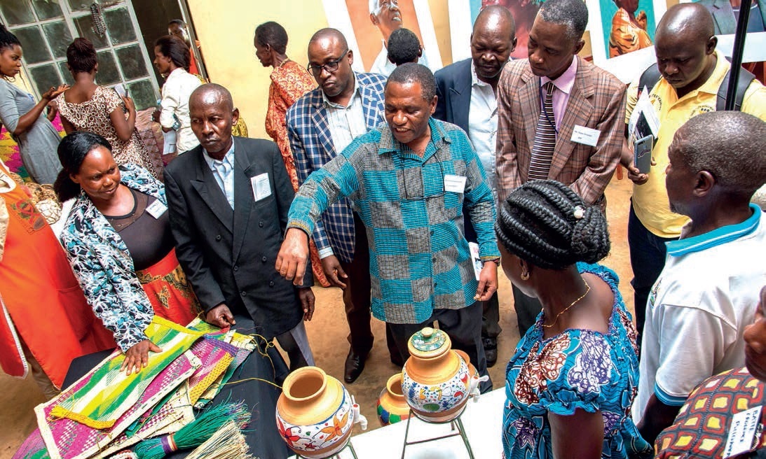 Mr. Bruno Sserunkuma-A Fine Artist who worked with the eldery (Centre gesturing) shows off some of the crafts developed to Dr. Isaac Lwanga-IDI (2nd Left Brown suit), Mr. Arthur Namara, ED-Health Nest UgandaHENU (3rd Left Checkered Jacket) and other attendees during the Exhibition held on 20th September 2019, Nansana Municipality, Wakiso Uganda.