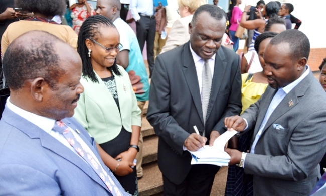The Deputy Chief Justice Alfonse Owiny-Dollo (2nd Right) assisted by Executive Secretary UNIFOG-Mr. Bruce Balaba Kabaasa (Right) autographs the Gender Equality Reports and Toolkit for Practitioners as Vice Chancellor-Prof. Barnabas Nawangwe (Left) and PI GEP-Assoc. Prof. Sarah Ssali witness on 10th April 2019, SFTNB Conference Hall, Makerere University, Kampala Uganda.