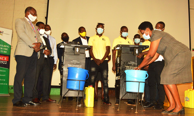 Vice Chancellor Prof. Barnabas Nawangwe (Left) looks on as Dr Rosemary Byanyima, Deputy Executive Director of Mulago National Referral Hospital wash hands using one of the kits donated to Mulago National Referral Hospital on 24th August 2020 at Main Hall- Makerere University. Touchless Hand-washing (Tw-20) Kit is a responsive technology to the COVID-19 Pandemic.The Tw-20 was developed with funds from Mak Research Innovation Fund.