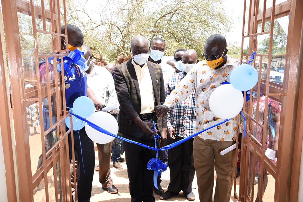 The RDC Pakwach-Mr. Toko Shuaib (Right) and another official cut the tape as the Project Manager, IDI West Nile Health Project-Dr. Twaha Mahaba (Left) witnesses at the unveiling of the newly renovated ART Clinic of Alwi Health Centre III, Pakwach District, Uganda on 13th August 2020. Photo credit: IDI