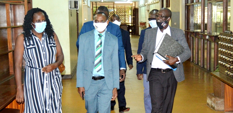 Deputy University Librarian-Dr. Ruth Nalumaga (L) leads the NCHE's Dr. Ayine Robert (R) and the team through a section of the Old Library. DVCAA-Dr. Umar Kakumba (2nd L) presented on Makerere University's readiness to undertake emergency ODeL and personally took the inspectors around Campus facilities