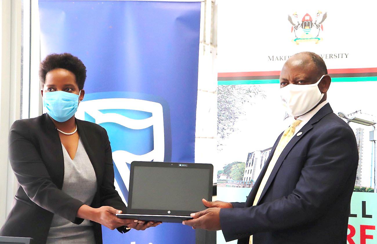 The Vice Chancellor-Prof. Barnabas Nawangwe (R) receives one of the laptops from Stanbic Bank CEO-Anne Juuko (L) during the handover of the donation on 14th October 2020, CTF1, Makerere University, Kampala Uganda.