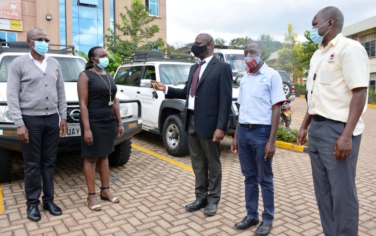 IDI Executive Director-Dr. Andrew Kambugu (C) hands over the vehicles to officials from Baylor Uganda (L) earlier this week at the IDI-McKinnell Knowledge Centre, Makerere University, Kampala Uganda.