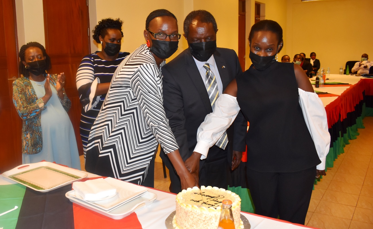 Incoming Ag. DVCFA-Dr. Josephine Nabukenya (3rd R) and outgoing Ag. DVCFA-Prof. William Bazeyo (2nd R) are joined to cut cake by Prof. Bazeyo’s daughter (R) as staff from the Office of the DVCFA (Rear) applaud at the handover ceremony on 30th November 2020, CTF1, Makerere University, Kampala Uganda.