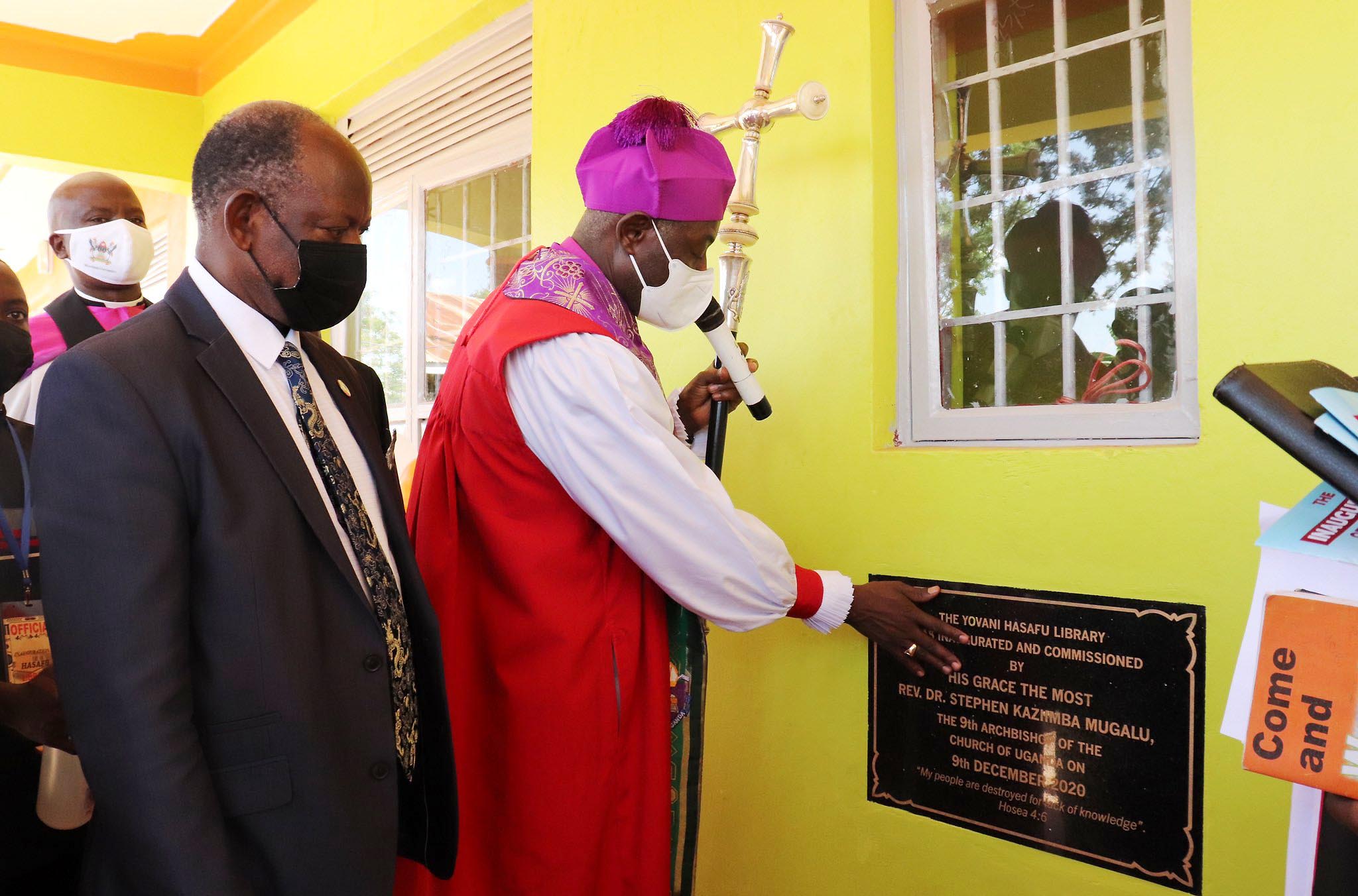 The Vice Chancellor-Prof. Barnabas Nawangwe (L), St. Francis Chaplain-Rev. Can. Onesimus Asiimwe (Rear) and other officials witness as the Archbishop, Rt. Rev. Dr. Stephen Kaziimba Mugalu commissions the Yovani Hasafu Library on 9th December 2020, Busia Integrated Primary School, Busia Uganda.