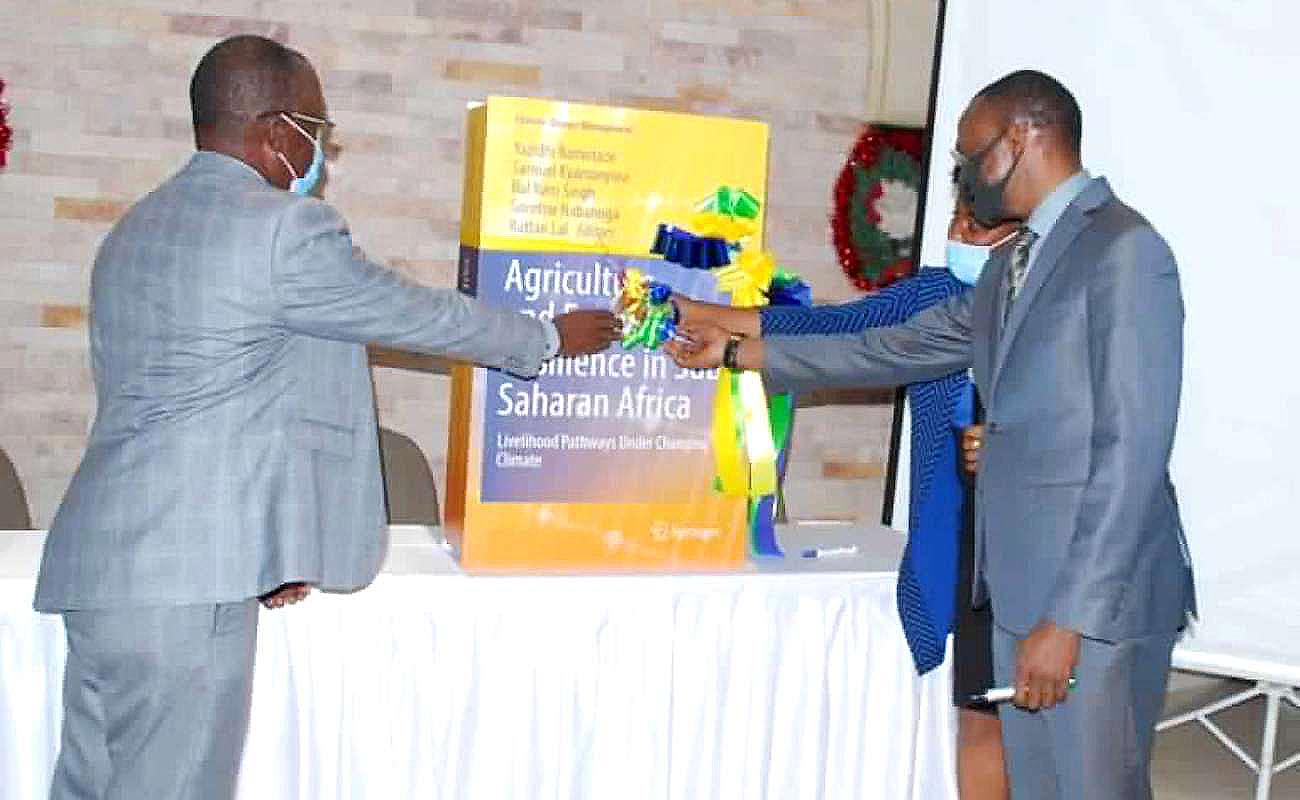 The DVCAA-Dr. Umar Kakumba assisted by CAPSNAC PI-Prof. Samuel Kyamanywa (L) and CAES Deputy Principal-Dr. Gorettie Nabanoga (R) cuts the ribbon to signify the book launch on 4th December 2020, Kampala Uganda.