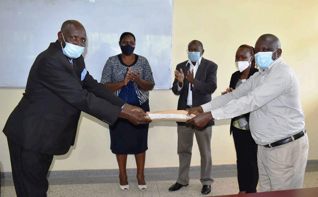 Outgoing Ag. Farm Manager-Mr. Tweyambe Chrysostom (L) hands over his report to the incoming Ag. Farm Manager-Dr. Stephen Lwasa (R) as Principal CAES-Prof. Bernard Bashaasha (C), Internal Auditor-Ms. Joan Mutekanga (2nd L) and Outgoing Ag. Director-Dr. Alice Turinawe (2nd R) witness on 2nd February 2021, MUARIK, CAES, Makerere University, Wakiso Uganda.