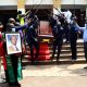 Chairperson MUASA-Dr. Deus Kamunyu Muhwezi bears the framed photo as pallbearers carry the late Prof. Anthony Kerali’s remains out of St. Augustine through an arch of clubs mounted by fellow golfers after the Requiem Mass on 23rd February 2021, St. Augustine Chapel, Makerere University.