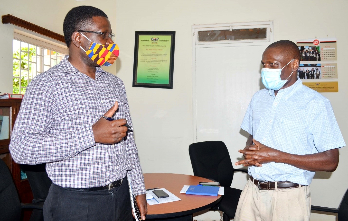 Assoc. Prof. Joseph Ochieng (R) and Dr. John Barugahare (L) chat during the dissemination of study findings on 'Ethical And Social issues for COVID-19 vaccine priority setting and access in Uganda’, 19th March 2021, Anatomy Department, CHS, Makerere University.