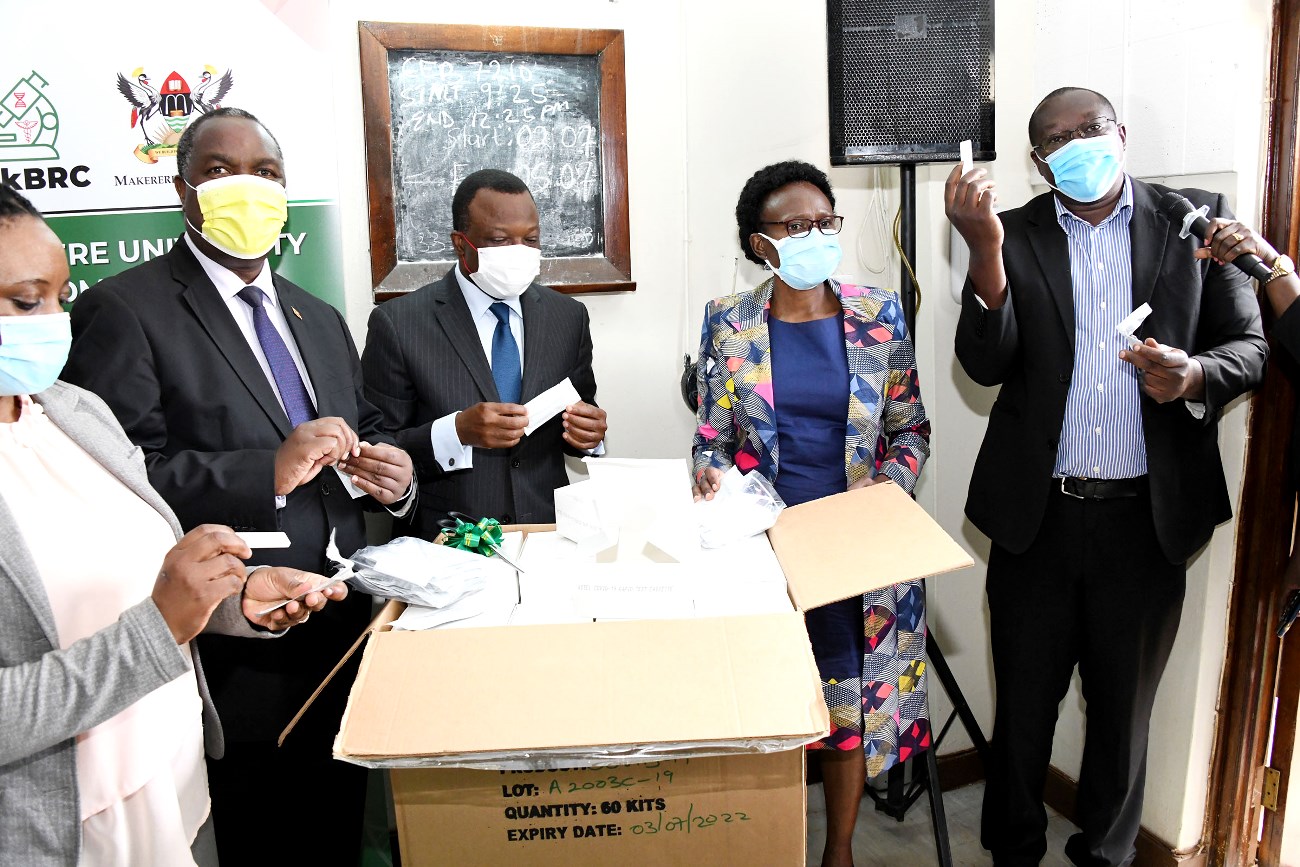 French Ambassador to Uganda-H.E. Jules-Armand Aniambossou (C) flanked by Hon. Dr. Jane Ruth Aceng (2nd R), Hon. Dr. Elioda Tumwesigye (2nd L) and Prof. Damalie Nakanjako (L) listen as Dr. Misaki Wayengera (R) unveils the COVID-19 Rapid Antibody Test Kits on 17th March 2021, CHS, Makerere University.