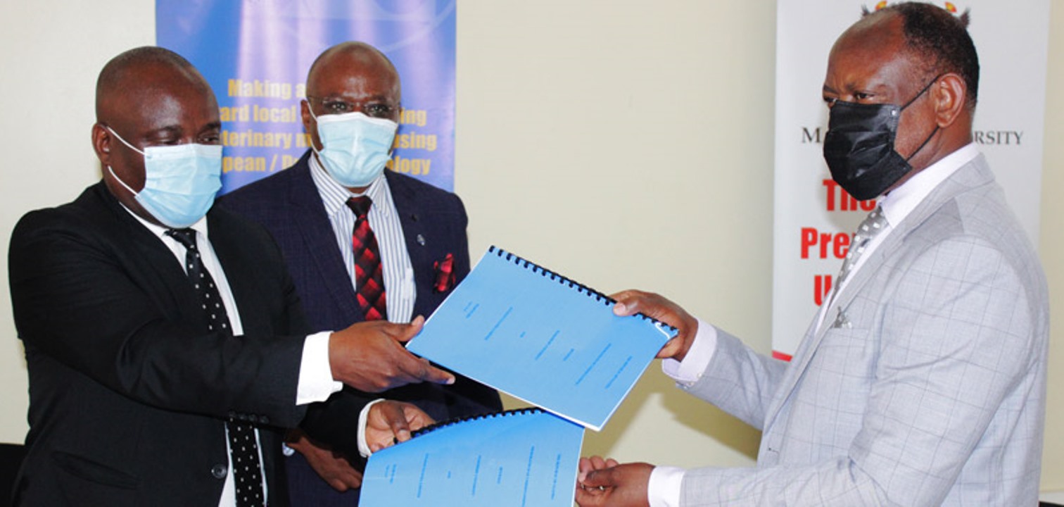 Managing Director Alfasan Uganda Ltd. Dr. Steven Birungi (Left) and the Vice Chancellor, Prof. Barnabas Nawangwe (R) exchange signed copies of the MoU as Canon Goddy Muhumuza, the Ag. Manager Intellectual Property Management Office witnesses on 19th March 2021, College of Veterinary Medicine, Animal Resources and BioSecurity (CoVAB).