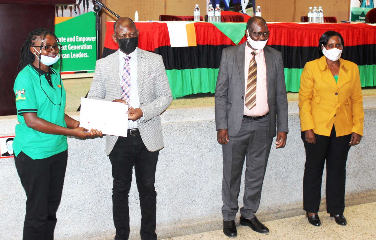 The Vice Chancellor, Prof. Barnabas Nawangwe (2nd L) presents the Award to a female beneficiary as MCFSP Coordinator-Dr. Justine Namaalwa (R) and MCFSP Selection Committee Chairperson-Dr. Muhammad Ntale (2nd R) witness on 12th March 2021, CTF2 Auditorium, Makerere University.
