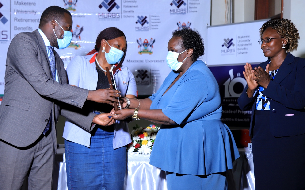 URBRA’s Mrs. Ritah Nansasi Wasswa (2nd L) assisted by Ag. University Secretary-Mr. Yusuf Kiranda (L) hands over a plaque of recognition to Outgoing Trustee-Ms. Dorothy Nannozi Kabanda (2nd R) as Incoming Trustee-Ms. Franco Angida Mugyema (R) applauds during the MURBS Board Handover on 26th March 2021.
