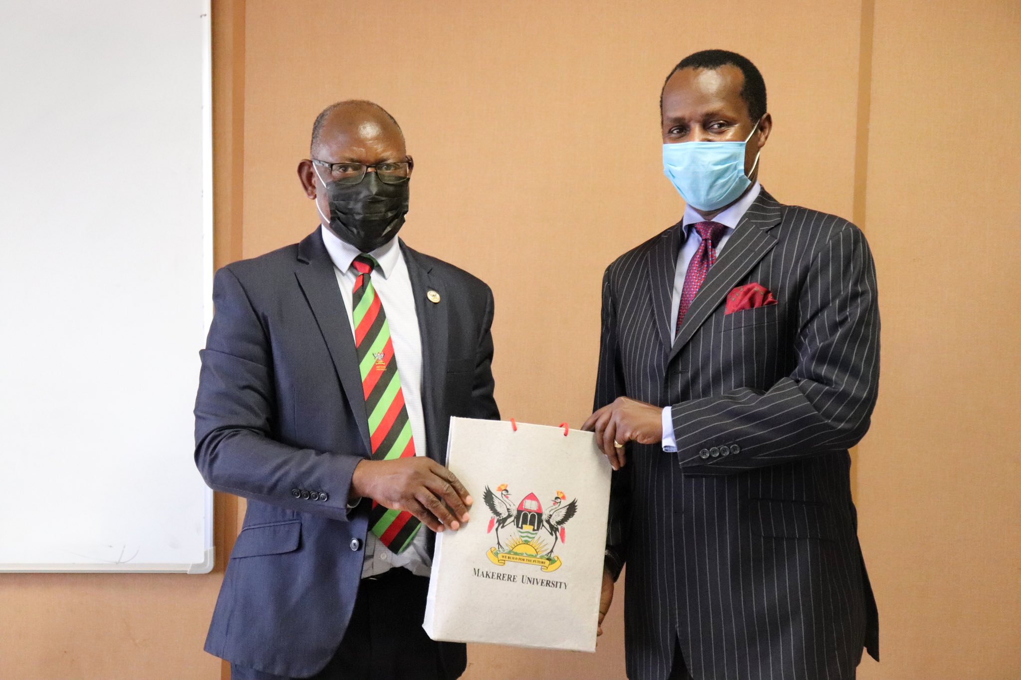 The Vice Chancellor, Prof. Barnabas Nawangwe (L) hands over Makerere University souvenirs to Prince David Wasajja following their meeting on 20th April 2021, Central Teaching Facility 1 (CTF1)
