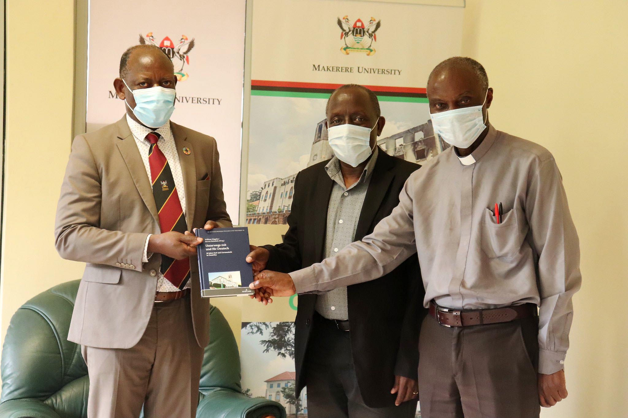 The Vice Chancellor, Prof. Barnabas Nawangwe (L) receives the book Unterwegs mit und für Deutsch: 50 Jahre DaF und Germanistik in Ostafrika from Dr. William Wagaba (C) and Rev. Prof. Manuel Muranga John Kamugisha (R) on 29th March 2021, CTF1, Makerere University.