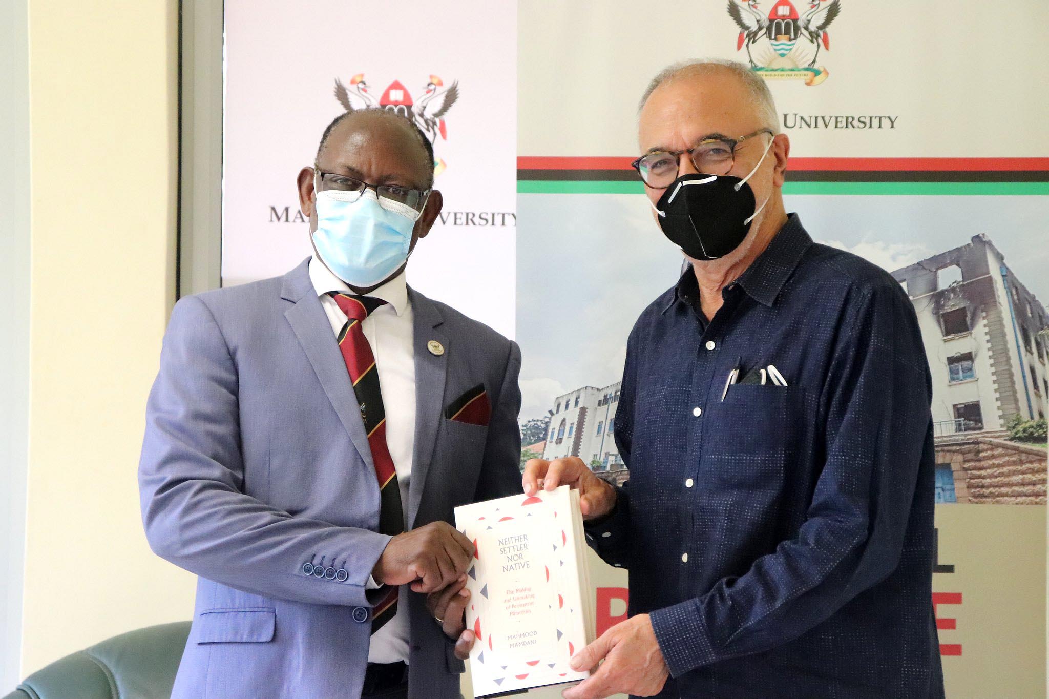 The Vice Chancellor, Prof. Barnabas Nawangwe (L) receives a copy of the book - Neither Settler nor Native: The Making and Unmaking of Permanent Minorities - from Prof. Mahmood Mamdani (R) on 1st April 2021, CTF1, Makerere University.