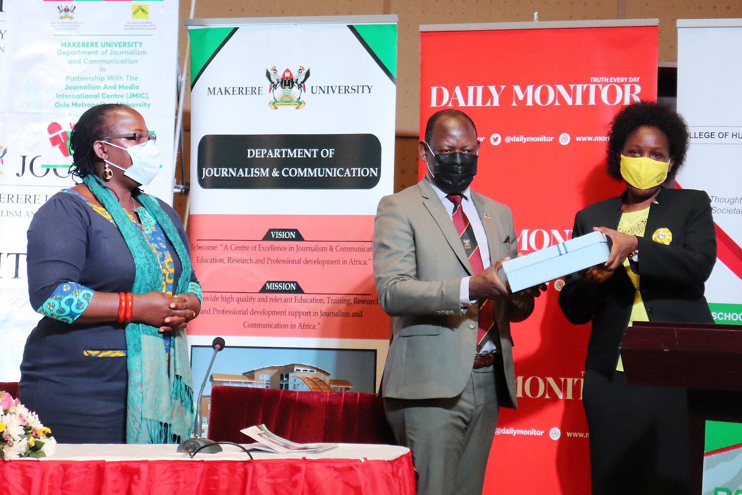 The Vice Chancellor, Prof. Barnabas Nawangwe (C) hands over a gift to the Minister of ICT and National Guidance-Hon. Judith Nabakooba (R) during the Annual Media Convention as Principal CHUSS-Dr. Josephine Ahikire (L) witnesses on 3rd May 2021, CTF2 Auditorium, Makerere University.