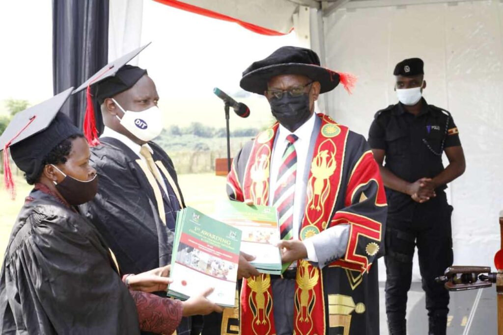 The Vice Chancellor-Prof. Barnabas Nawangwe (R) receives graduation books of the cohorts from Director DIT, MoES-Mr. Byakatonda Patrick (C) and Deputy Commissioner Social Services Development, MoES-Madam Elizabeth Bateme (L). 
