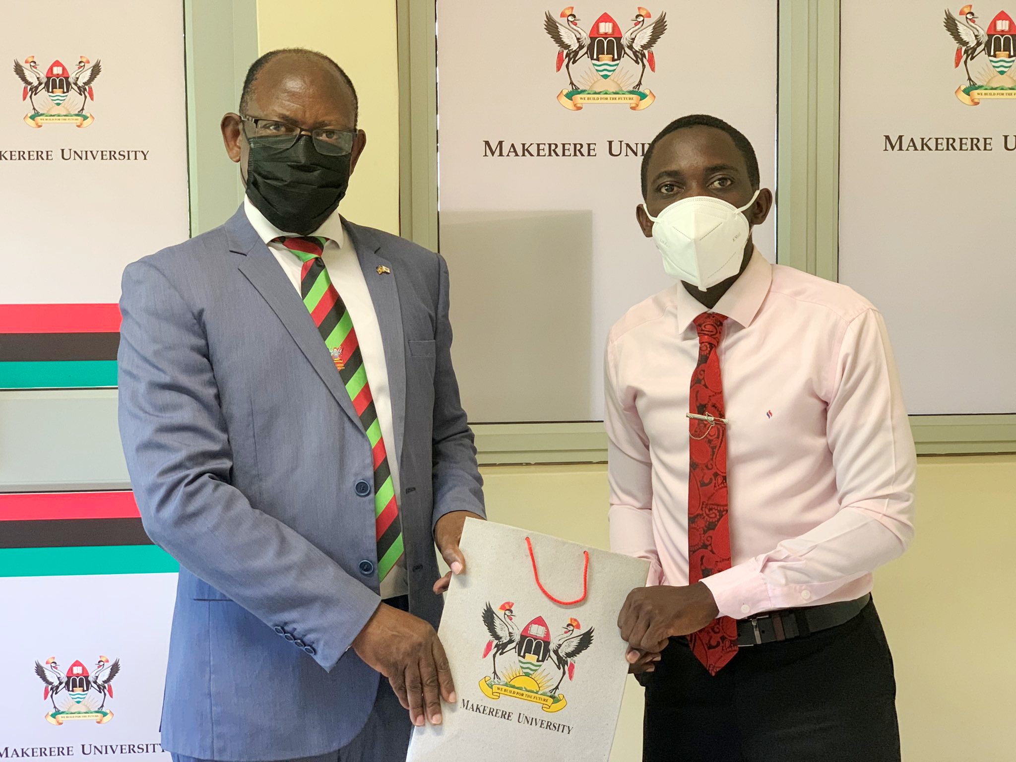 The Vice Chancellor, Prof. Barnabas Nawangwe (L) hands over an assortment of Mak souvenirs to the 86th Guild President Mr. Ssempijja Ivan (L) after their meeting, June 2021, CTF1, Makerere University.