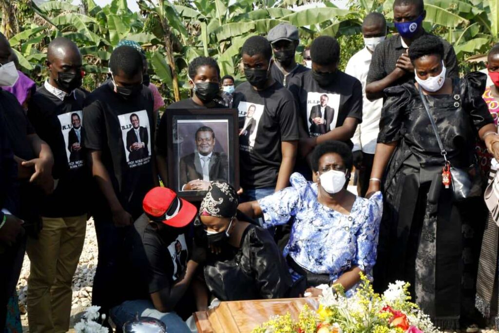 Mrs. Dr. Beatrice Banadda supported by relatives and surrounded by her children at Prof. Banadda's graveside. 