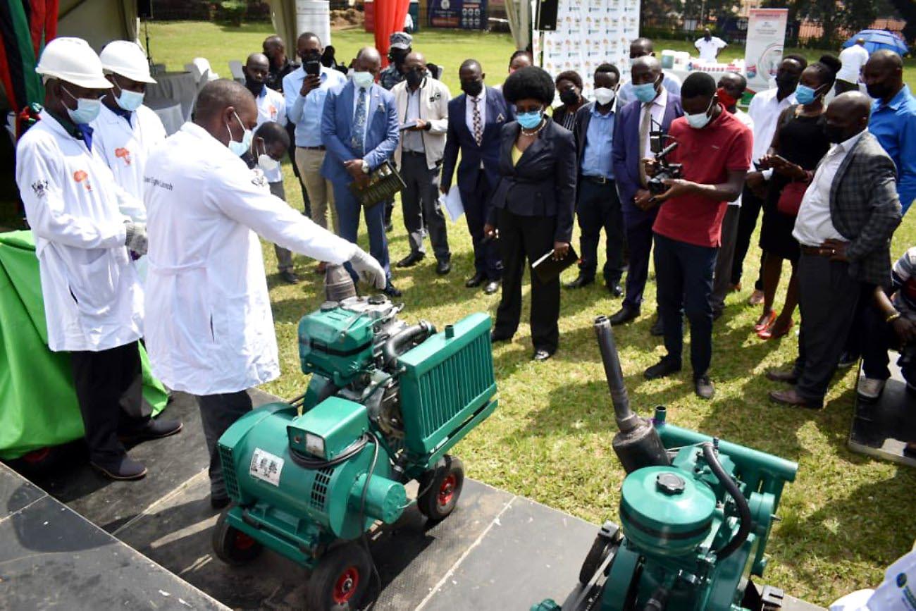 The Minister of Science, Technology and Innovation, Hon. Dr. Monica Musenero (Centre), Vice Chancellor, Prof. Barnabas Nawangwe and other guests listen to M/S Kevoton’s representative explain how one the #MakDieselPower engine prototypes works during the launch on 19th August 2021, Freedom Square, Makerere University.