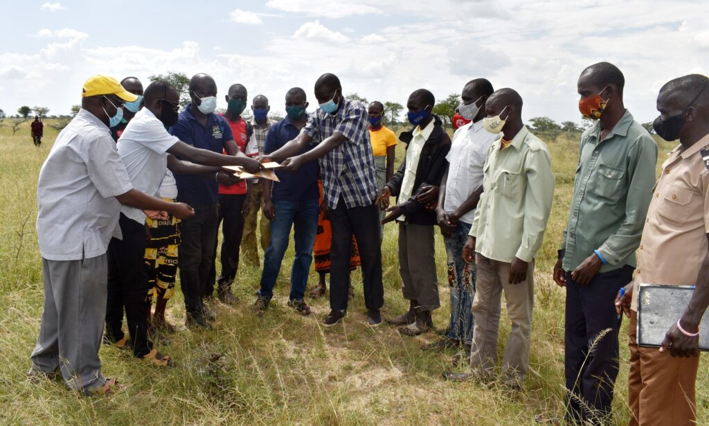 The LCIII Chairman Poron Sub-County, Mr. Angella John (in checked shirt) hands over the Drylands Transform project site to the Napak District Officials.