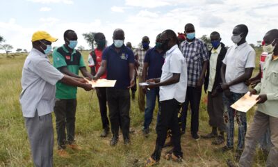 Napak and Moroto District officials (in blue and green t-shirts) hand over the site in Poron Sub-County, Napak to the Drylands Transform project Principal Investigator-Prof. Denis Mpairwe (L) on 23rd October 2021.