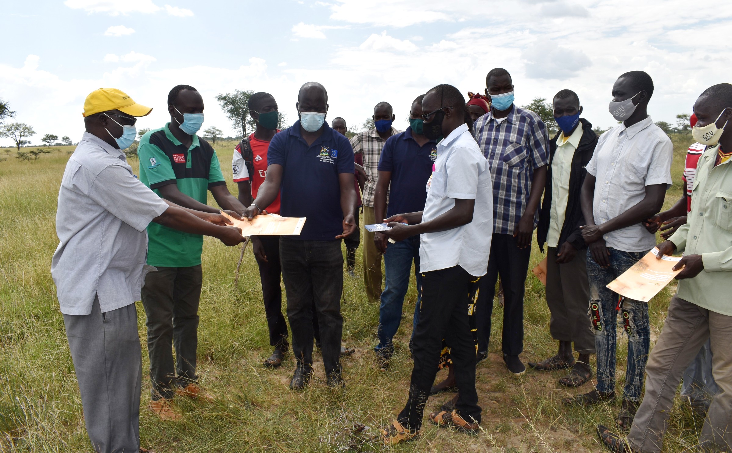 Napak and Moroto District officials (in blue and green t-shirts) hand over the site in Poron Sub-County, Napak to the Drylands Transform project Principal Investigator-Prof. Denis Mpairwe (L) on 23rd October 2021.