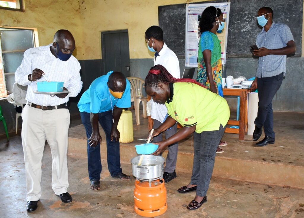 Dr. Immaculate Nakalembe (in green) prepares one of the soups under the watchful eye of participants in Kigorobya sub-County, Hoima District.