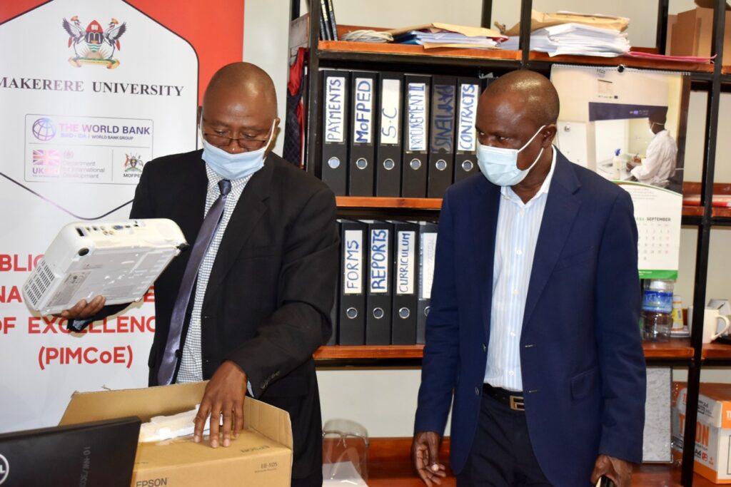 Interim PIM CoE Manager Dr. Willy Kagarura (L) unveils some of the procured equipment at the PIM CoE as Assoc. Prof. Eria Hisali (R) witnesses.