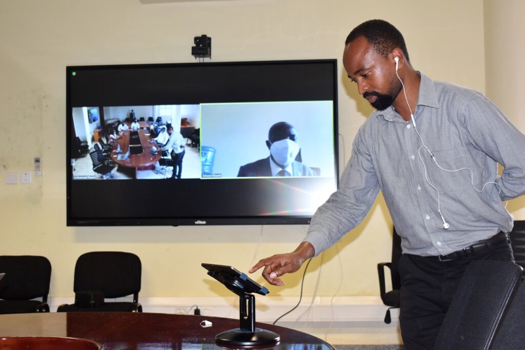 An IT personel walks participants through some of the interactive smart board's features using an iPad.