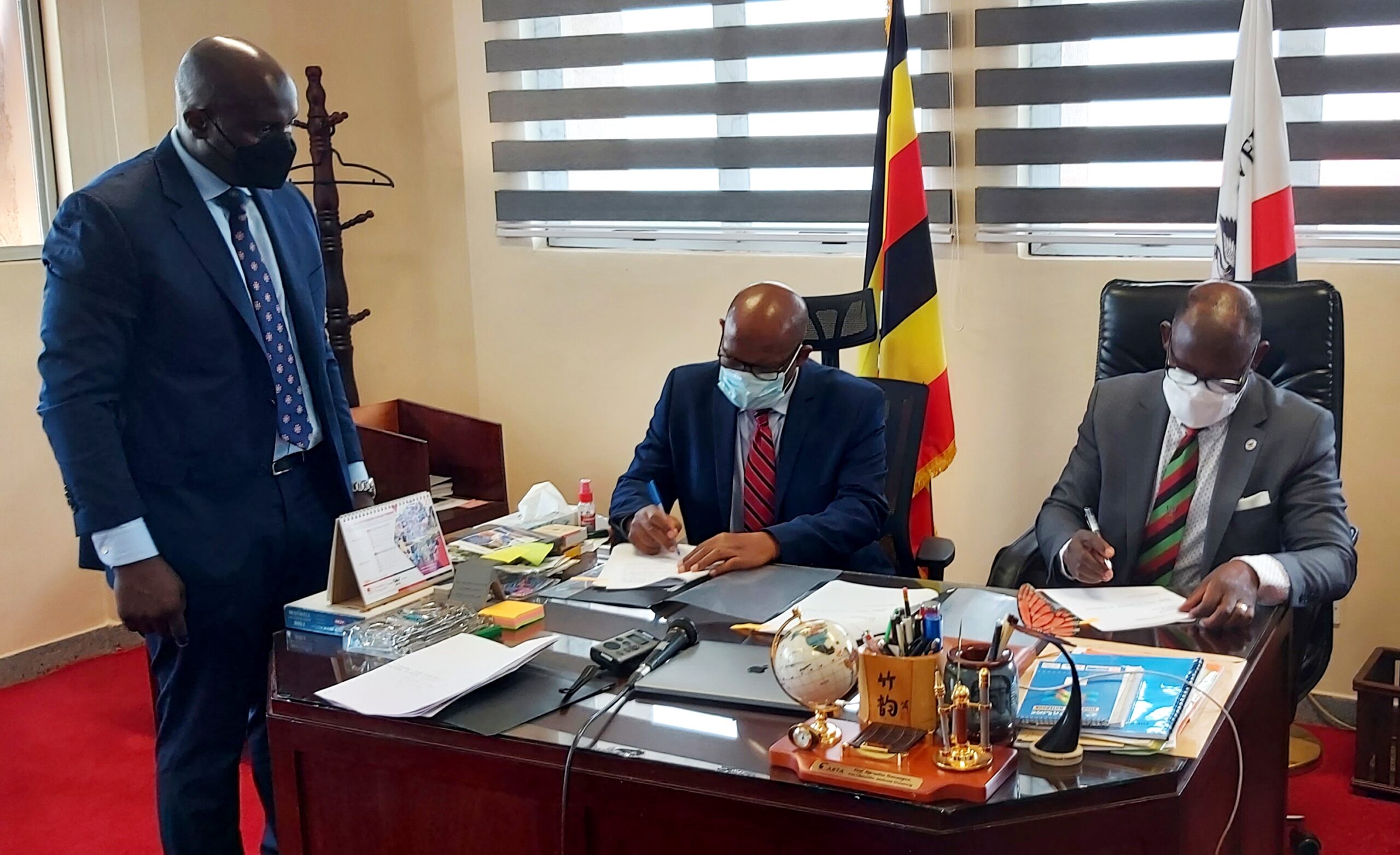 The Vice Chancellor, Prof. Barnabas Nawangwe (R) and Mr. Cephas Birungi Kagyenda (C) sign the MoU on behalf of Makerere University and UHTTI respectively as Director Legal Affairs, Mr. Javason Kamugisha (L) witnesses on 22nd October 2021, CTF1, Makerere University.