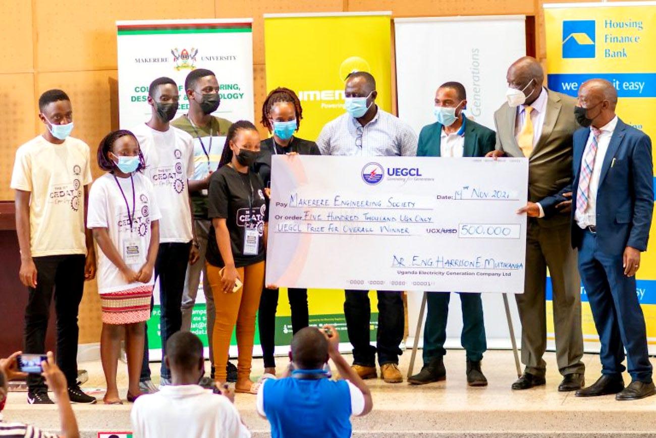 The Minister of State for Minerals-Hon. Peter Lokeris (2nd R) together with the Principal CEDAT-Prof. Henry Alinaitwe and UEGCL Officials hand over a dummy cheque to the best exhibitor of the 10th Annual CEDAT Open Day and MES@50 Celebrations held 19th-20th November 2021.