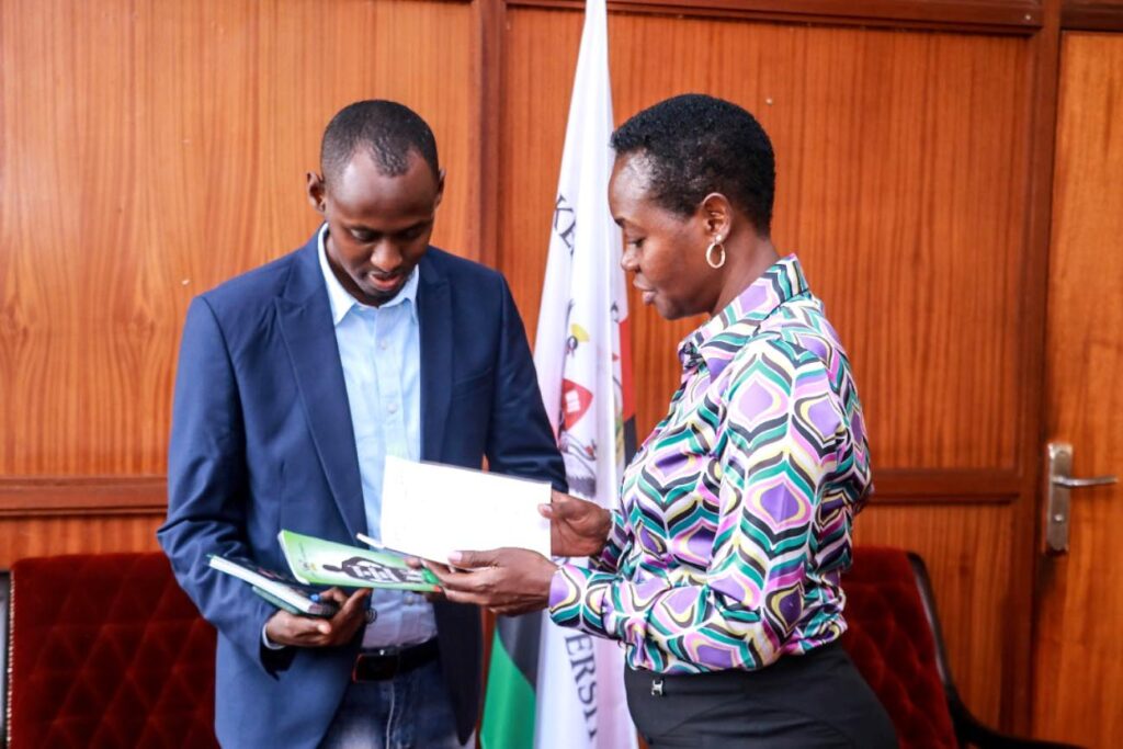 Mrs. Winifred Kabumbuli (R) presents some of the policies and manuals to Mr. Ismail Abdullahi Ibrahim (L).