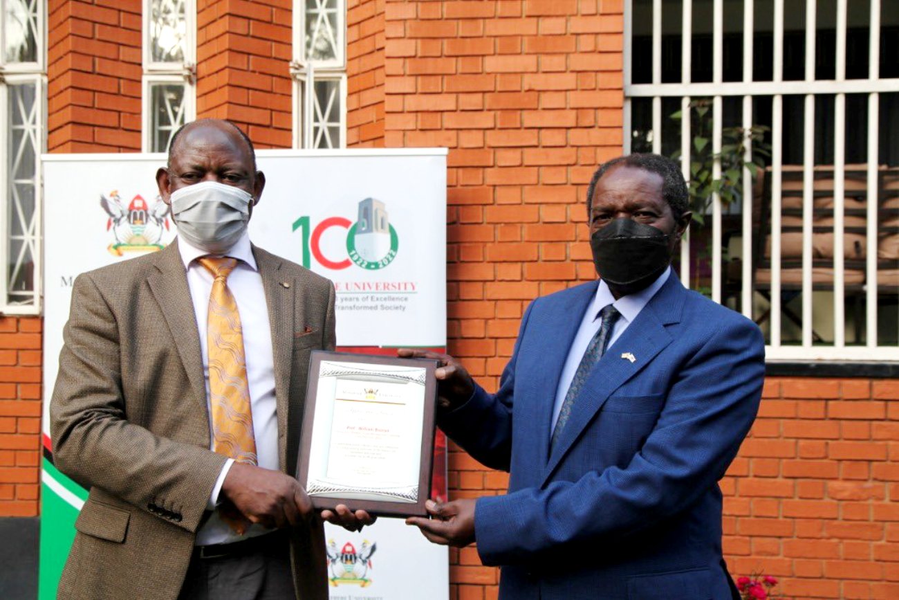 The Vice Chancellor, Prof. Barnabas Nawangwe (L) presents a plaque to Prof. William Bazeyo (R) in recognition of his service to Makerere University on 22nd December 2021.