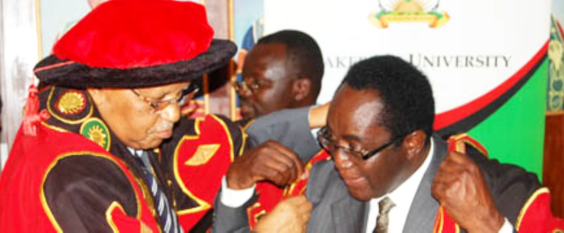 The Chancellor, Prof. Mondo Kagonyera (L) robes the new Vice Chancellor, Prof. John Ddumba Ssentamu (R) with his official gown during the handover ceremony on 6th September 2012, Council Room, Makerere University.