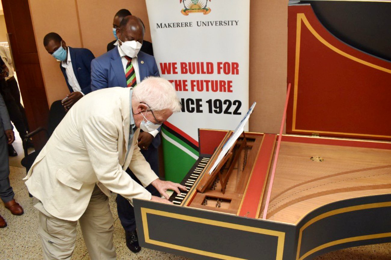 Prof. Hugh Rowell plays a tune on the Harpsichord as the Vice Chancellor, Prof. Barnabas Nawangwe listens shortly after he handed over the instrument on 27th January 2022 in the Council Room, CTF1, Makerere University.