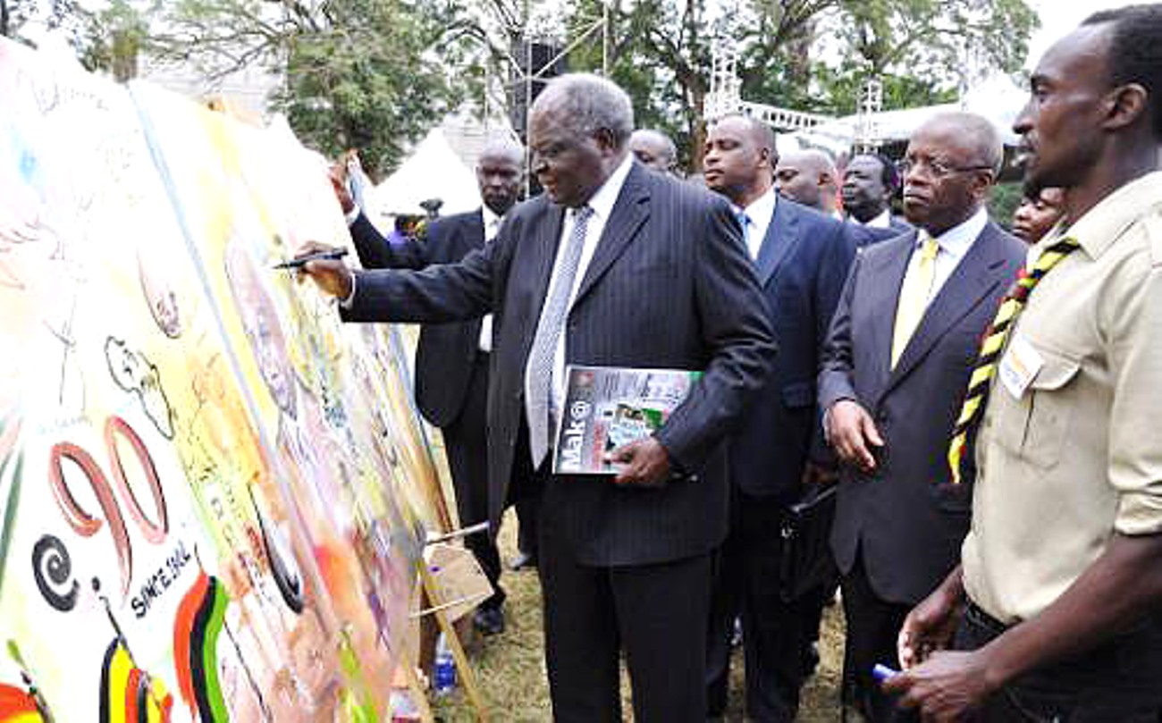 Former Kenyan President H.E. Mwai Kibaki signs the Live painting commemorating the 90 Years of Makerere accompanied by the Chief Guest Rt. Hon. Amama Mbabazi (2nd R) at the Mak@90 Grand Finale Celebrations 3rd August 2013, Makerere University, Kampala Uganda.