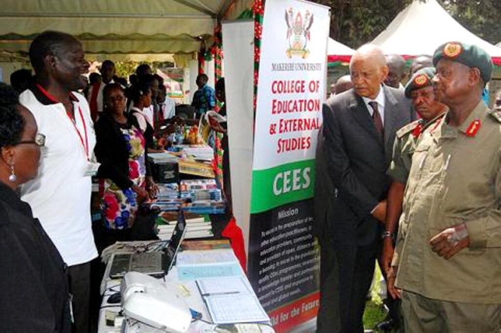 The E-Learning Manager Mr. Titus Okumu (2nd L)  explains the platform's importance to President Museveni as he visited the College of Education and External Studies (CEES) stall during his tour of the exhibition.