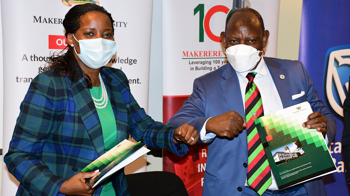 The Vice Chancellor Prof. Barnabas Nawangwe (R) and Stanbic Bank Chief Executive Officer Ms Anne Juuko (L) bump elbows after signing the Laptop hire purchase scheme Memorandum of Understanding at Central Teaching Facility 1(CTF1)-Makerere University on 15th February 2022.