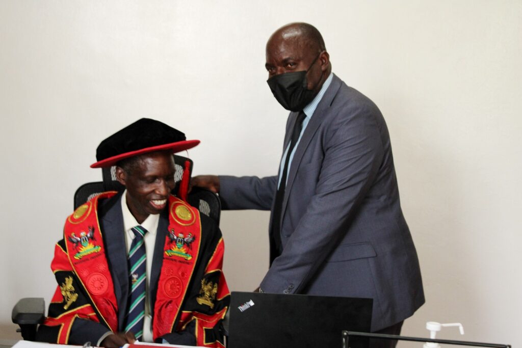 Prof. Fred Masagazi Masaazi (R) helps Prof. Anthony Muwagga Mugagga (L) into the Principal's seat after handing over office. 