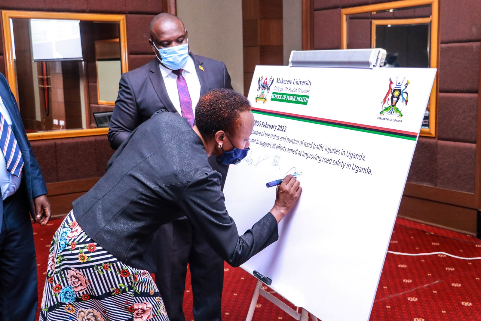 Hon. Naome Kabasharira, the Rushenyi County Constituency MP (R) appends her signature on the commitment from MakSPH to promote road safety in Uganda as Hon. Tonny Ayo, the MP for Kwania County, and Vice chairperson Parliamentary committee on Road Safety (2nd R) witnesses on 17th February 2022 during the breakfast meeting at the Kampala Sheraton Hotel.