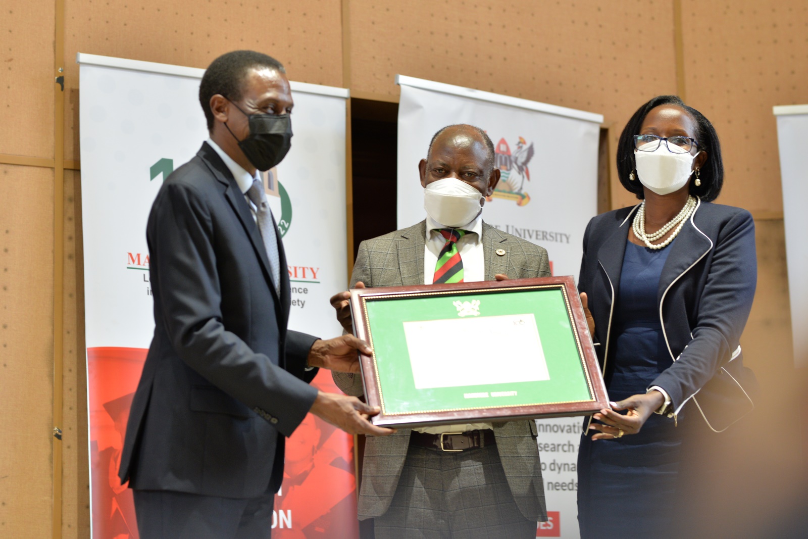 The Attorney General, Hon. Kiryowa Kiwanuka (L) receives his Eminent Service Award from Council Chairperson, Mrs. Lorna Magara (R) and Vice Chancellor, Prof. Barnabas Nawangwe (C).