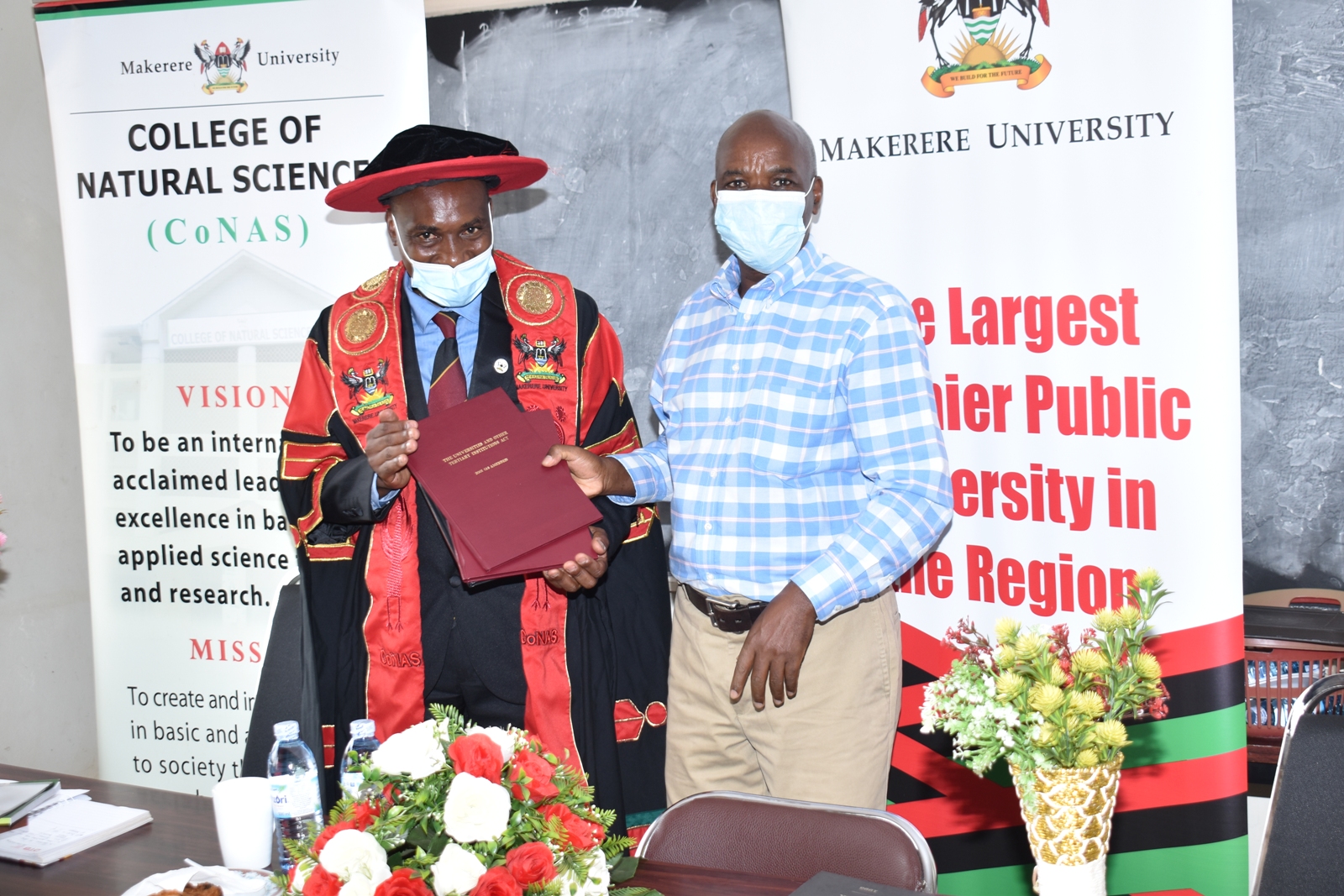 Outgoing Principal CoNAS, Prof. J.Y.T. Mugisha (R) hands over some of the instruments of power to Incoming Principal, Assoc. Prof. Winston Tumps Ireeta (L) on 8th February 2022.