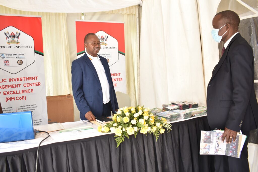 Dr. Willy Kagarura (L) receives Prof. Eria Hisali at the PIM CoE Exhibition Booth during the Open Day.