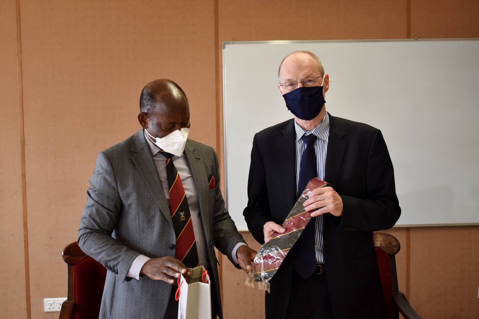 The Vice Chancellor, Prof. Barnabas Nawangwe (L) presents the Mak necktie and an assortment of souvenirs to WUN Executive Director, Dr. Peter Lennie (R) during his visit to Makerere University on 21st March 2022, Council Room, CTF1.