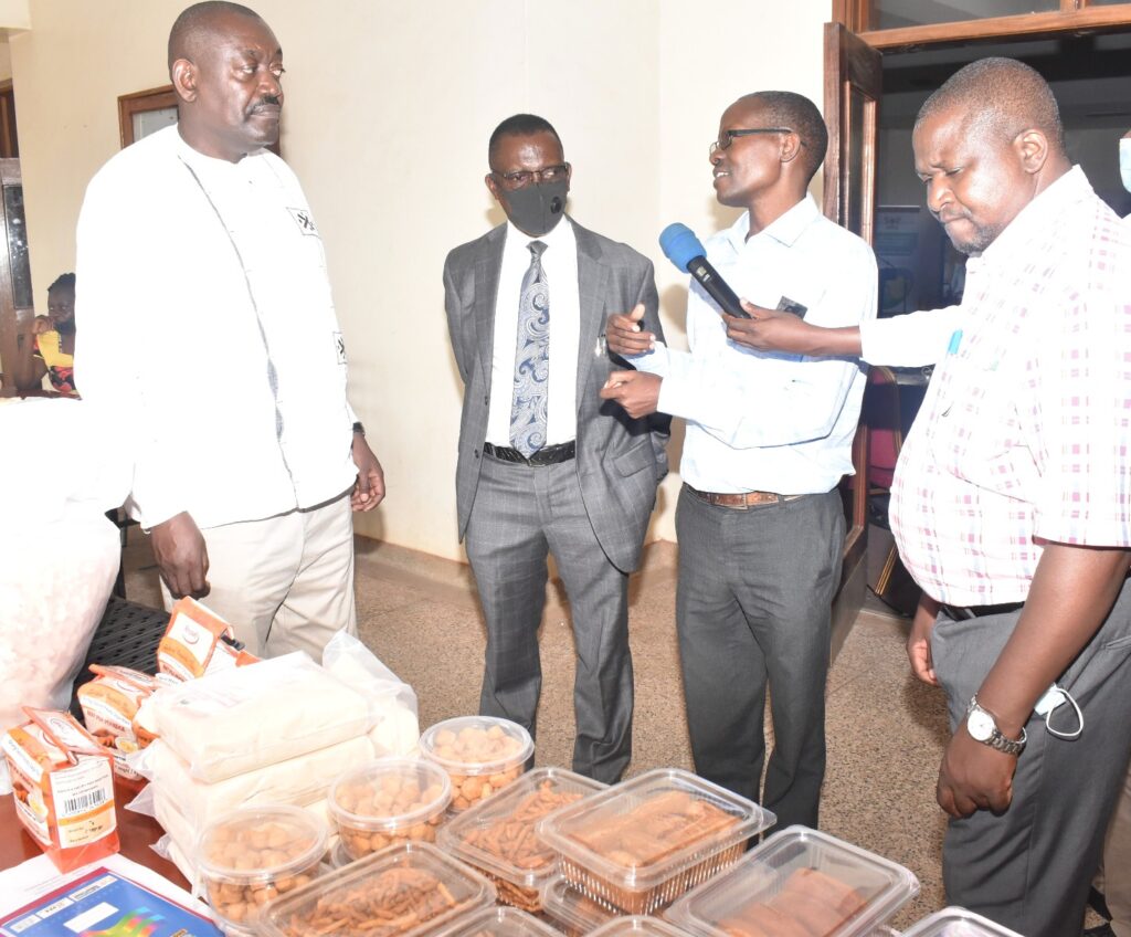 Dr. Settumba Mukasa (2nd R) briefs the Commissioner in charge of Crop Inspection and Certification at the MAAIF, Mr Paul Mwambu (L) on some of the products developed.