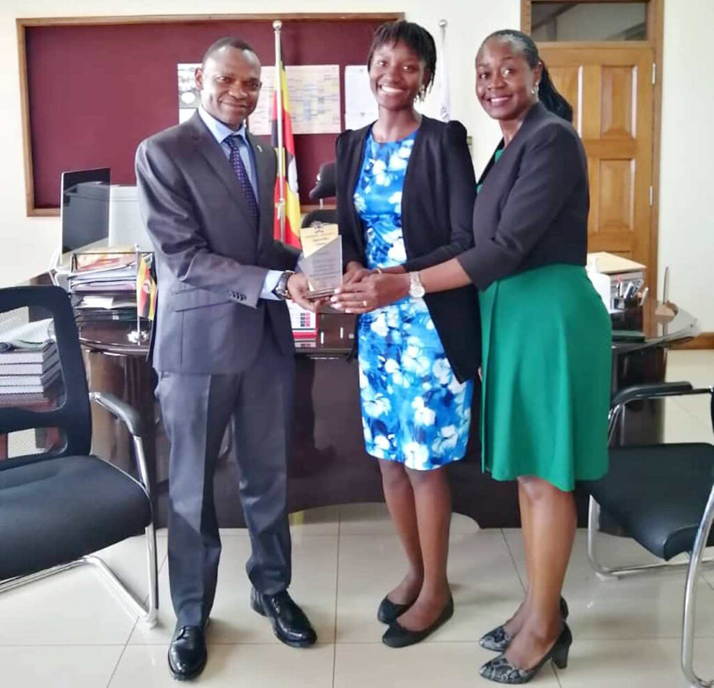 Prof. Umar Kakumba (L) and Mrs. Winifred Kabumbuli (R) present the award to the 86th Guild Speaker, Ms. Angel Kampi (C) during the ceremony. 