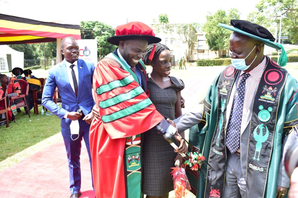Dr. Denis Okello, Head, Department of Physics (R) congratulates one of the PhD graduands