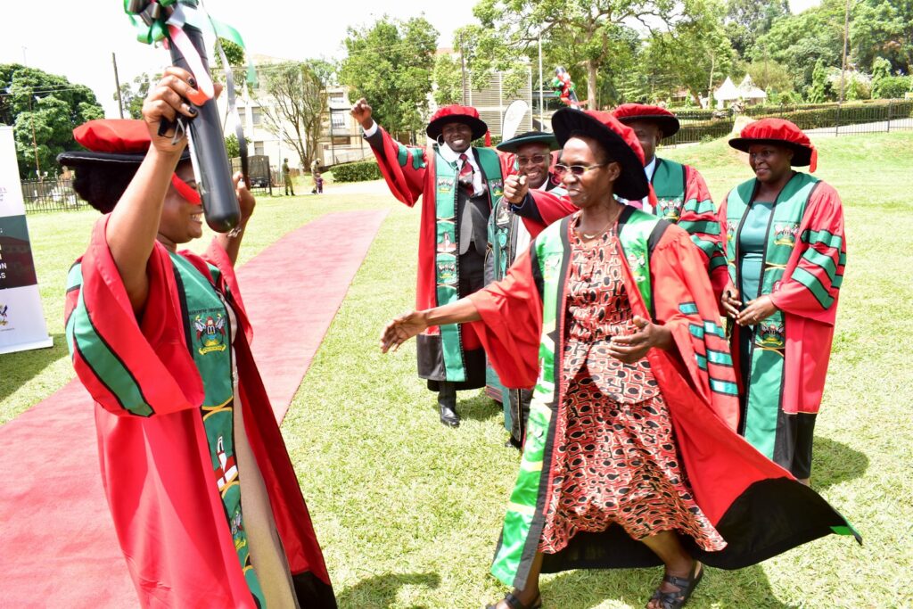 Prof. Esezah Kakudidi (2nd R) prepares to embrace one of the PhD Graduands from CoNAS (L).